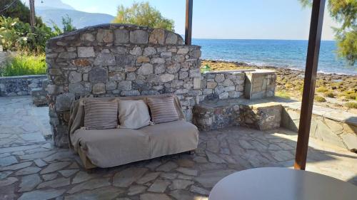 a couch sitting in front of a stone wall at Seaside Apartment in Agios Nikolaos