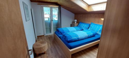 ein Schlafzimmer mit einem Bett mit blauen Kissen und einem Fenster in der Unterkunft Chalet Sunnmätteli in Wilderswil