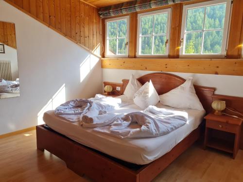 Bett in einem Zimmer mit 2 Fenstern in der Unterkunft Alpina Mountain Resort in Sulden
