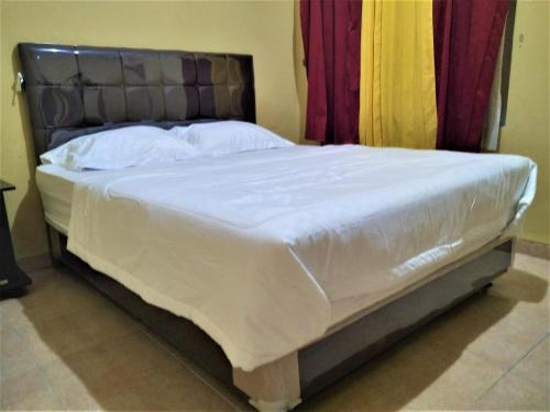 - une chambre dotée d'un lit avec des draps blancs dans l'établissement Hotel Pekalongan Syariah Mitra RedDoorz, à Pekalongan