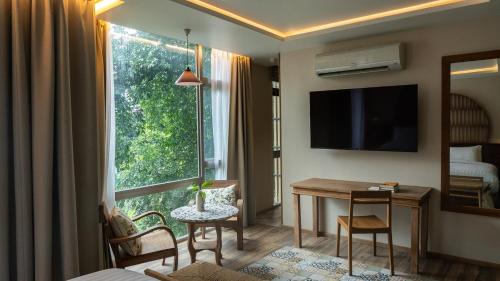 Una sala de estar con una mesa y una gran ventana. en Tints of Blue Hotel, en Bangkok