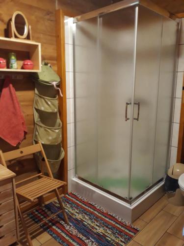 a glass shower in a room with a wooden chair at Chata u Sylwii in Okuninka
