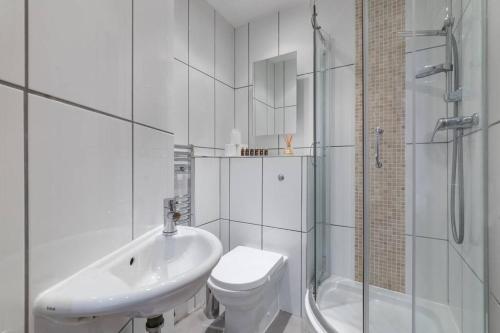 een badkamer met een wastafel, een toilet en een douche bij Home For All - Fitzrovia - by Frankie Says in Londen