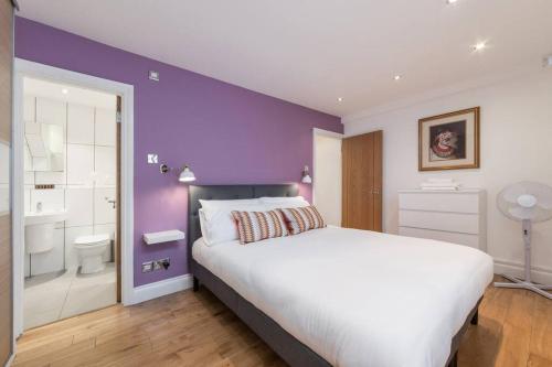 een slaapkamer met een groot bed en een paarse muur bij Home For All - Fitzrovia - by Frankie Says in Londen