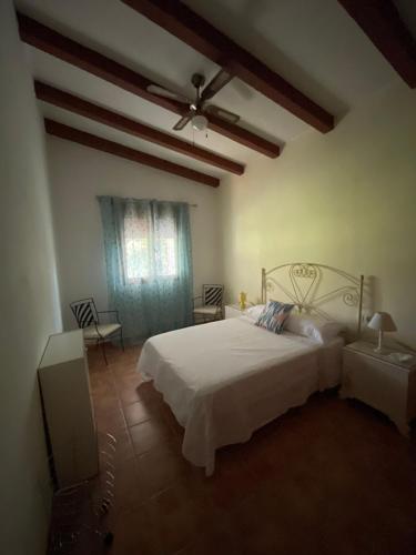 una camera con letto bianco e ventilatore a soffitto di Cortijo CANO a Cuevas del Almanzora