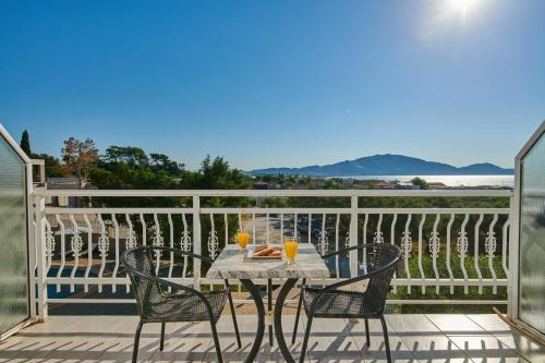 a table and chairs on a balcony with two glasses at Armonia Hotel by Zante Plaza in Laganas