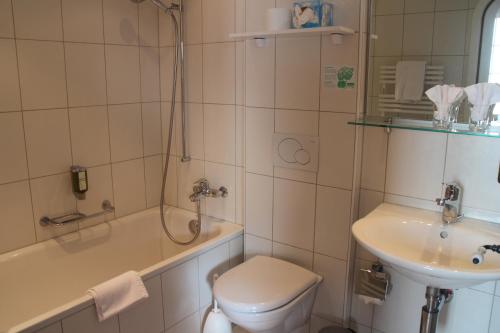 a bathroom with a sink and a toilet and a tub at Hotel Sonnenberg in Grindelwald