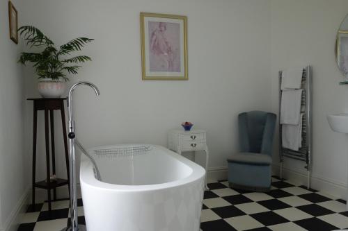 a bath tub in a bathroom with a black and white floor at The East Wing in Glasbury