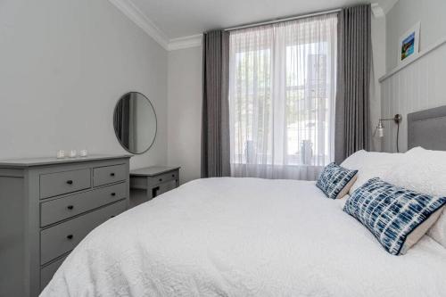 a white bedroom with a bed and a window at 14 South Street in St Andrews