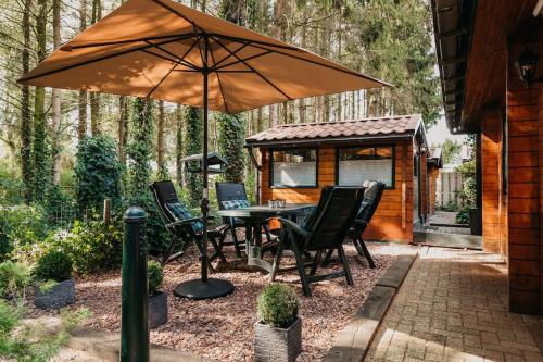 a table and chairs under an umbrella on a patio at Cosy and romantic forest house in Putten