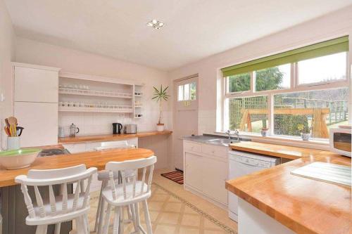 a kitchen with white cabinets and a table and chairs at Kittocks Den in St Andrews