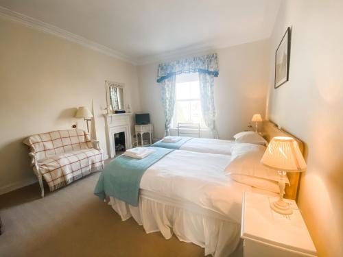 - une chambre avec un grand lit blanc et une chaise dans l'établissement Sandmill, Murray Park, à St Andrews