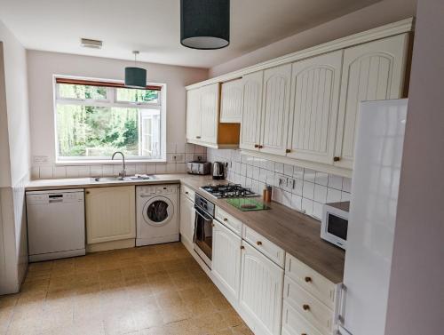 a kitchen with white cabinets and a washer and dryer at Rosebank in St. Andrews