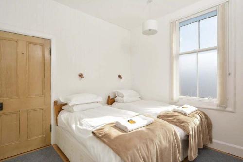 Heywood Cottage في سانت أندروز: سريرين في غرفة بجدران بيضاء ونافذة