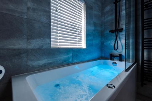 een blauwe badkamer met een bad en een raam bij Faulkner House in Chester