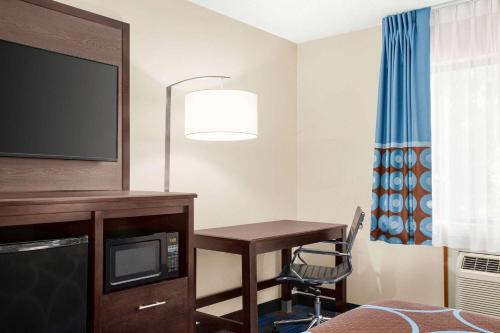 a hotel room with a desk and a tv and a table at Super 8 by Wyndham Lenexa Overland Park Area/Mall Area in Lenexa