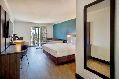 a hotel room with a bed and a desk and a mirror at Studio 6 Suites Lawndale, CA South Bay in Lawndale