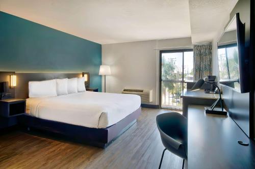 ローンデールにあるStudio 6 Suites Lawndale, CA South Bayのベッド、デスク、窓が備わるホテルルームです。
