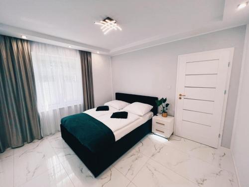 sypialnia z czarno-białym łóżkiem i oknem w obiekcie Apartament Latarników Stilo w Sasinie