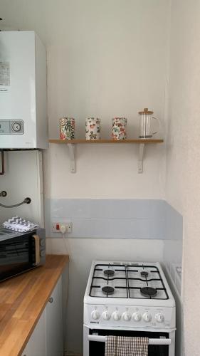 a kitchen with a stove and a microwave at Cosy Wirral home near Liverpool with Free Parking! in Birkenhead