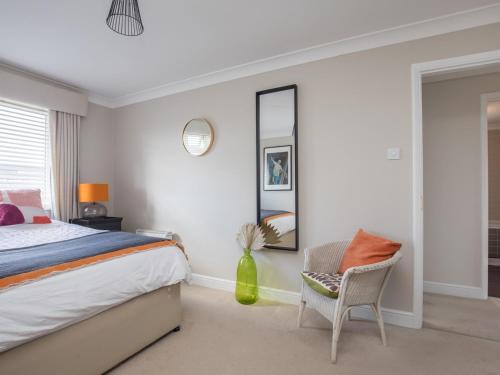 um quarto com uma cama, uma cadeira e um espelho em Pass the Keys Stylish 2 Bedroom Flat Apartment with Free Parking in Windsor em Windsor
