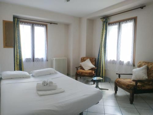 a bedroom with a large white bed and two chairs at Classic House in Argentat