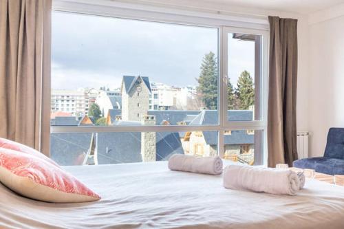 um quarto com uma grande janela e uma cama com almofadas em ESTUDIO A 20M DEL CENTRO CIVICO- VISTA AL LAGO em San Carlos de Bariloche
