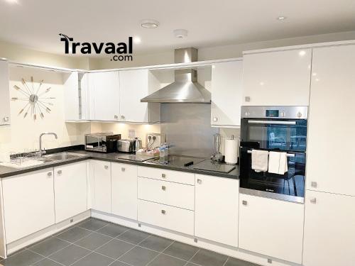 eine weiße Küche mit weißen Schränken und Geräten in der Unterkunft Travaal.©om - 2 Bed Serviced Apartment Farnborough in Farnborough