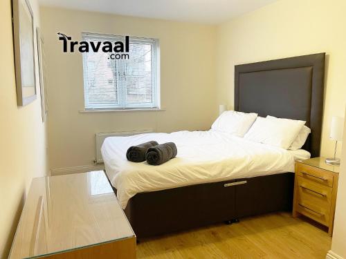 ein Schlafzimmer mit einem großen Bett mit zwei schwarzen Objekten darauf in der Unterkunft Travaal.©om - 2 Bed Serviced Apartment Farnborough in Farnborough