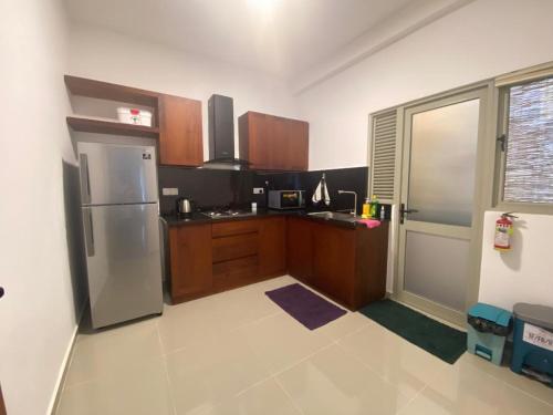 a kitchen with a stainless steel refrigerator and wooden cabinets at 3 Bedroom Apartment, Ariyana Resort in Athurugiriya