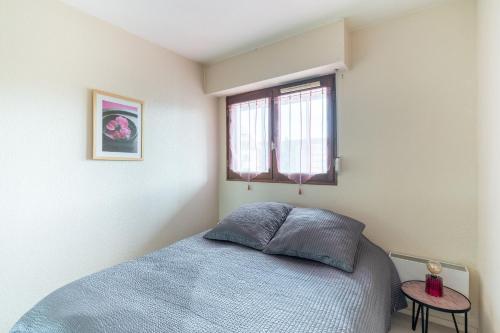 - une chambre avec un lit bleu et une fenêtre dans l'établissement Le Grand Cap, à Villers-sur-Mer