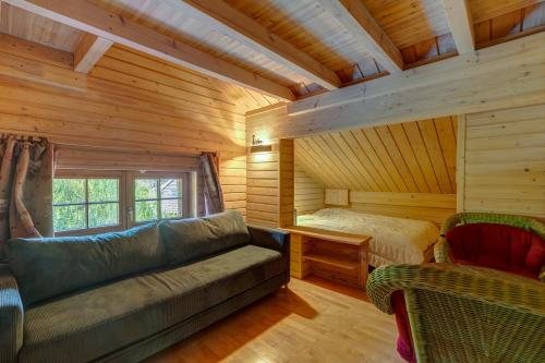 una sala de estar con sofá y una cama en una cabaña de madera en La Forge, en Manigod