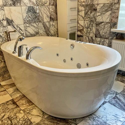 a white bath tub in a bathroom with tiles at Zatyshok in Vinnytsya