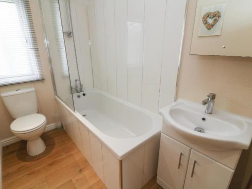 La salle de bains blanche est pourvue de toilettes et d'un lavabo. dans l'établissement Waterside Lodge, à Carnforth
