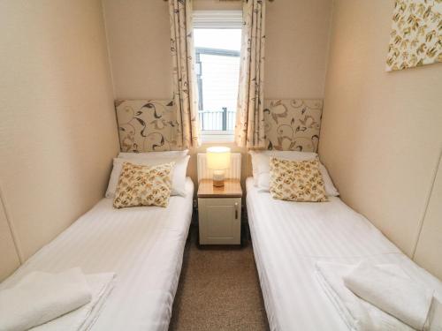 deux lits jumeaux dans une chambre avec fenêtre dans l'établissement Waterside Lodge, à Carnforth