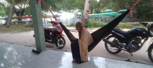 a woman sitting in a hammock next to a motorcycle at Homestay Buang Sari in Gresik