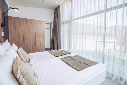 a bedroom with a white bed and a large window at Tri lučke Hotel & Restaurant in Krško