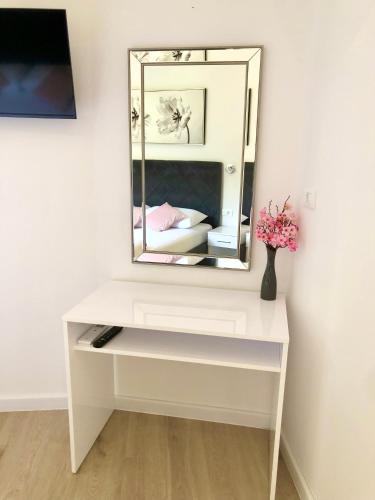 um toucador branco com um espelho e um vaso de flores em Hotel B&B CHAMBERLAIN em Hvar