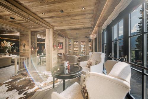 a living room with white chairs and a table and windows at Alpin Resort Sacher in Seefeld in Tirol