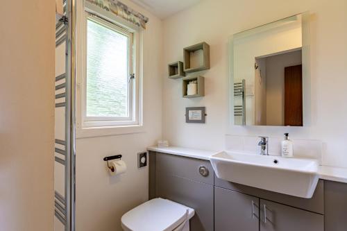 uma casa de banho com um lavatório, um WC e uma janela. em Bracken Lodge 7 with Hot Tub em Belladrum