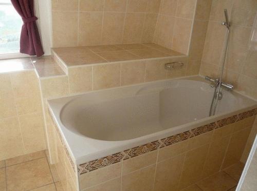 a white bath tub in a tiled bathroom at La Cameline in Plougasnou