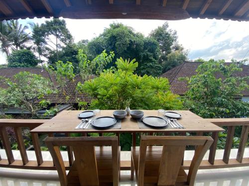 a wooden table with plates and utensils on a porch at Umah Nik Kepitu in Gianyar