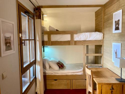 a room with two bunk beds and a desk at Appartement ARC 1950 m, Ski au pied, piscine extérieure chauffée, remontées mécaniques à 100m, sauna et salle de sports in Arc 1950