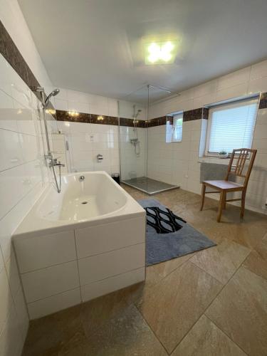 a bathroom with a tub and a chair in it at Relaxen im alten Winzerhaus Fewo OG in Rech