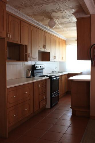 a kitchen with wooden cabinets and a stove top oven at Hotel Mount Maluti - Lesotho in Mohales Hoek