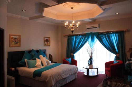 a bedroom with a bed with blue curtains and a window at Hotel Mount Maluti - Lesotho in Mohales Hoek