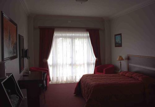a hotel room with a bed and a window at Hotel Mount Maluti - Lesotho in Mohales Hoek