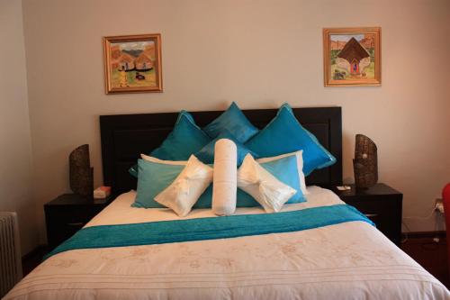 a bed with blue and white pillows on it at Hotel Mount Maluti - Lesotho in Mohales Hoek