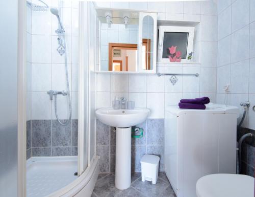a white bathroom with a sink and a shower at Sunset Apartment in Zaton