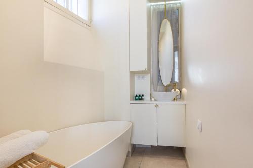 biała łazienka z wanną i umywalką w obiekcie Exceptional Haussmannian apartment- Heart of Paris w Paryżu
